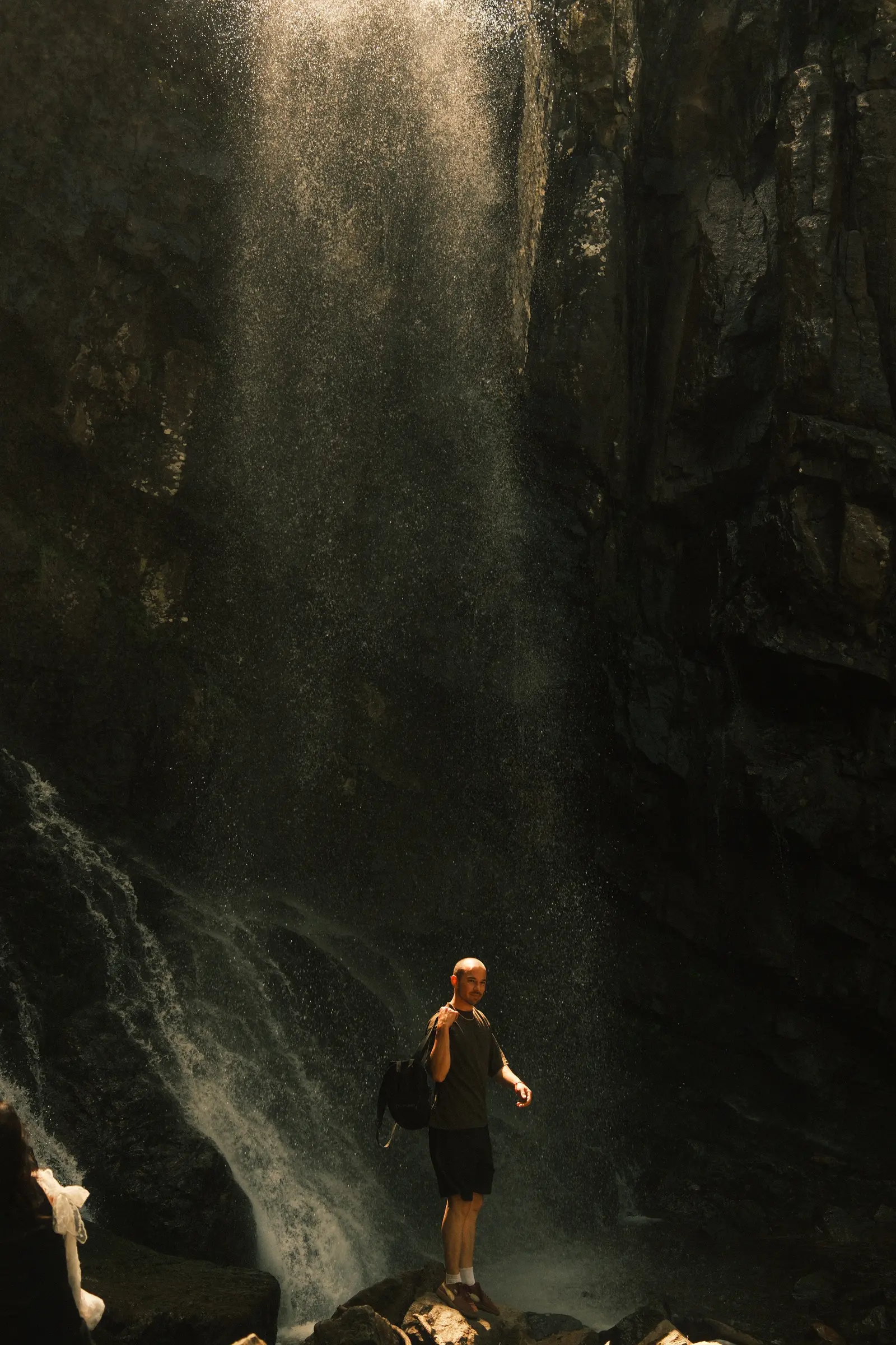 Figure beneath a mountain waterfall